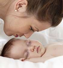 mom kissing baby sleeping